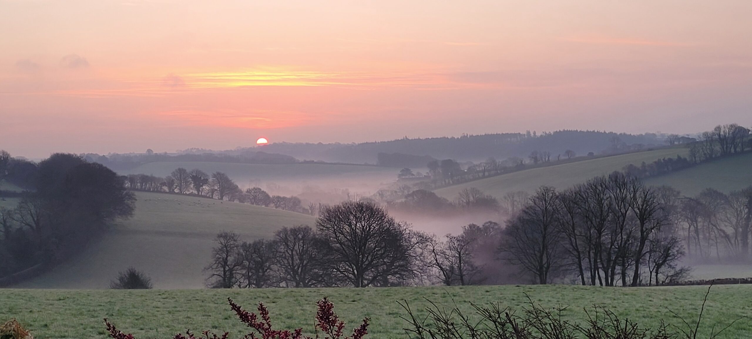 sunset over the valley with mist sitting heavily over the fields